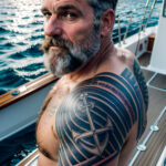 Как вес влияет на тату A man with a faded sailor tattoo on his bicep standing on a boat deck rugged look weathered skin gray beard classic anchor tatufoto.com 059