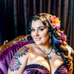 Как вес влияет на тату A plus-size woman with a colorful chest tattoo lounging on a velvet armchair wearing a strapless dress dark curly hair pinned tatufoto.com 183