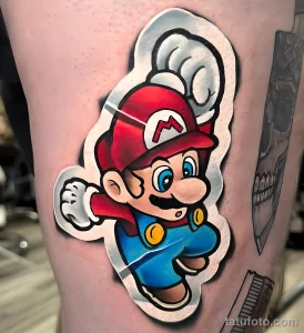 Фото тату с изображением Марио из игры Super Mario Bros на предплечье. Яркие цвета и динамичная поза персонажа.