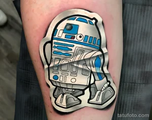 Фото тату: Детализированное изображение робота R2-D2 из "Звездных войн" на руке, выполненное в ярких цветах.