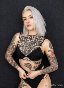 Фото тату на девушке: черная татуировка в стиле blackwork с геометрическими узорами и цветочными мотивами. Расположена на груди и руках.