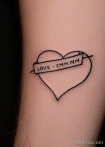 Черно-белое фото татуировки сердца с надписью "LOVE" на запястье, выполненной простым шрифтом.