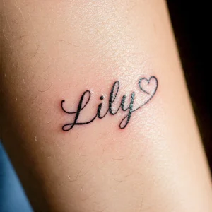 Фото тату с надписью 'Lily' выполненной красивым шрифтом и маленьким сердечком. Черные чернила, нежное и женственное.