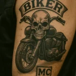 Фото тату черепа, сидящего на мотоцикле, с надписью 'BIKER MC'. Черно-серая татуировка на плече, популярная среди байкеров.