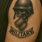 Фото тату с изображением черепа в каске, армейских жетонов и надписи 'MILITARY'. Черно-серая татуировка на плече, посвященная военной службе.