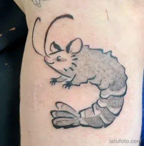 Фото тату: минималистичный рисунок креветки в технике blackwork на руке. Черная татуировка с использованием плотных заливок и четких линий.