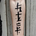 upper forearm macro, pale skin with scattered vitiligo, vertical runes in black ink stacked with fine cracks and weathered effec 2025 №57 - фото tatufoto.com