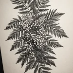 Фото тату ветки рябины, выполненной в технике blackwork. Детализированный рисунок татуировки с черными листьями и ягодами, выполненный в графичном стиле.