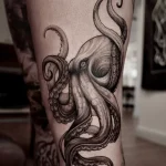 Фото тату: крупный осьминог, выполненный в технике blackwork, на голени. Акцент на детализацию щупалец и головы.