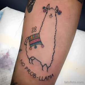 Черно-белое фото татуировки ламы с ярким седлом в полоску и надписью 'No Prob-Llama'. Тату выполнено в минималистичном стиле.
