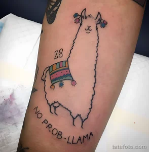 Фото тату: стилизованная альпака с забавной надписью 'No Prob-Llama', украшенная цветами. Расположена на предплечье.