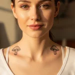 Фото тату: два симметричных мухомора на груди девушки. Минималистичный рисунок в черном цвете.