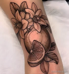 Фото тату: черно-белая татуировка апельсина с цветами в стиле blackwork на руке. Детализированная проработка теней и узоров.