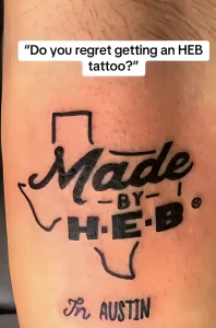 Фотография татуировки с надписью "Made by H-E-B in Austin" на руке человека, сделанной в черном цвете.