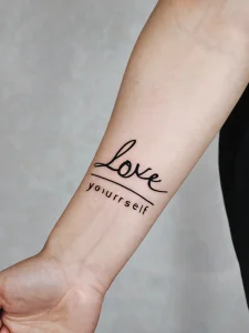 Фото тату надписи 'love yourself' на руке. Минималистичный дизайн, подчеркивающий важность самолюбия. Идеальный эскиз для тех, кто ценит простоту.