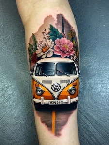Фото тату: красочный рисунок Volkswagen Bus, украшенного цветами, на руке, выполненный в реалистичном стиле.