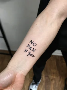 Фото тату с надписью 'No Pain No Gain' выполненной простым шрифтом на предплечье. Минималистичный дизайн и мотивационный посыл.