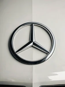 Татуировка, интегрирующая символ пацифика в логотип Mercedes-Benz, как ироничное выражение хиппи-капитализма, в стиле фотореализма.