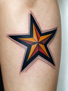 Фото татуировки на икре. Пятиконечная звезда, выполненная в стиле old school с использованием ярких цветов: желтого, красного и черного.