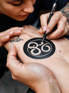 Фото тату: процесс нанесения татуировки с изображением символа Ом на руке. Детализированное фото тату.