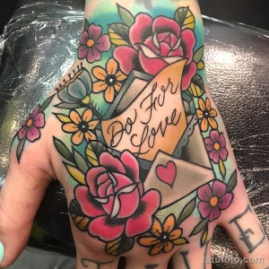 Фото яркой татуировки на руке: письмо с цветами и надписью 'Do For Love', в стиле олд скул.