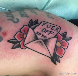 Фото тату на руке в стиле олд скул с изображением письма, роз и надписи 'Fuck Off'.