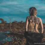 Фото тату: впечатляющая татуировка в виде корсета с костяными вставками и шнуровкой на женской спине, выполненная в реалистичном стиле. Эскиз тату для девушек.
