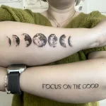 Фото тату: минималистичная татуировка фаз луны и надпись 'FOCUS ON THE GOOD' на предплечье. Вдохновляющий и стильный дизайн.