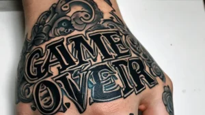 Черно-серая татуировка 'Game Over' с черепами и узорами, выполненная на руке. Детализированный рисунок татуировки в стиле олдскул.