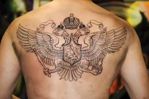 Фото тату двуглавого орла на спине мужчины, выполненного в контурной технике. Четкие линии и детализированный рисунок.
