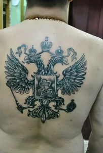 Фото реалистичной татуировки двуглавого орла на спине мужчины. Детализированный рисунок с проработкой перьев и теней.