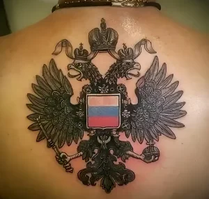 Фото татуировки двуглавого орла на спине мужчины. Черно-серый рисунок с акцентами в цветах российского флага.