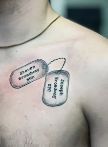 Фото тату на груди: два армейских жетона с именами. Черно-серый рисунок татуировки.