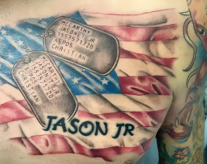 Фото тату на груди: американский флаг, два жетона с именем 'McCarthy Jason T. Jr' и надписью 'A POS CHRISTIAN'. Черно-серый и цветной рисунок, посвященный памяти.
