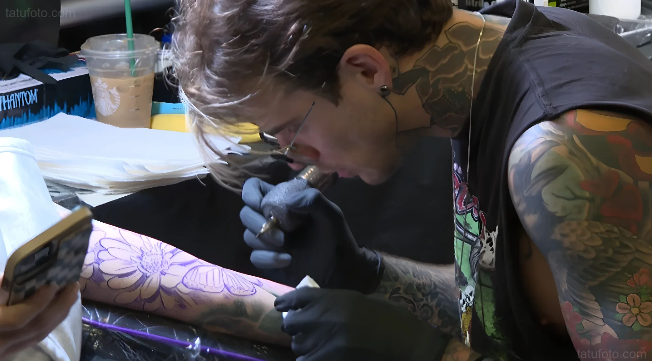 Тату-мастер делает татуировку на ноге посетителя на Resurrection Island Tattoo Convention в Wheeling