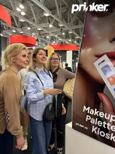 Женщины рассматривают киоск Prinker Makeup Palette Kiosk на выставке