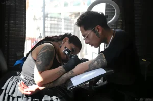 Daniela Artemisa tattooing a client's arm