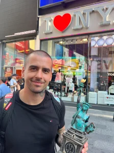 Misi Furucz, чемпион татуировки, с трофеем на фоне Times Square в Нью-Йорке