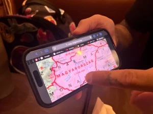Руки тату-мастера Миши Фуруча держат смартфон с картой Венгрии.