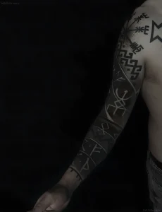 Фотография мужского рукава татуировки в стиле Blackwork, скандинавские руны, Вегвизир, точечная растушевка на черном фоне.