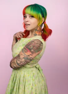 Lua Stardust, бразильская модель SuicideGirls, с яркими цветными татуировками на руке и шее, в панк-гламурном образе.