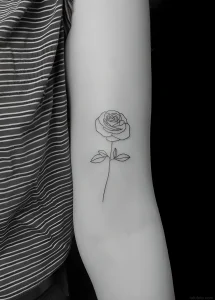 Минималистичная татуировка розы в стиле эскиза, выполненная черными линиями на руке