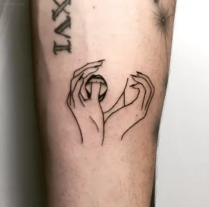 Черно-белая татуировка в стиле handpoke: две руки, держащие земной шар. Работа Тати Комптон.