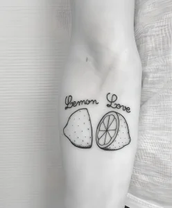 Татуировка в стиле эскиза от The Crayoner: лимоны и надпись 'Lemon Love'.