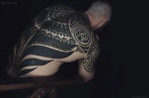 Крупный план мужской спины с плотной полинезийской татуировкой в стиле Blackwork, демонстрирующий сложные узоры и контраст.