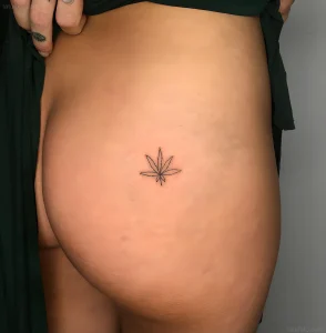 Минималистичная татуировка листа каннабиса в технике handpoke от Тати Комптон на боку