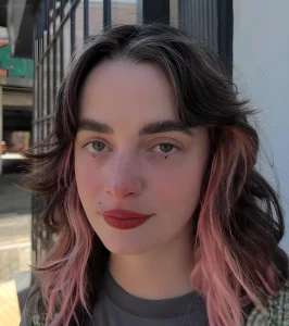 Девушка с минималистичными татуировками в виде капель под глазами, символизирующими пережитую боль и внутреннюю силу.