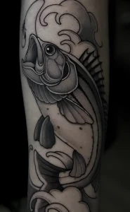 Черно-белая татуировка морского окуня на руке, выполненная в традиционном стиле с элементами волн и брызг.