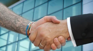 Рукопожатие бизнесмена с татуировкой на предплечье, символизирующее доверие и современный подход к бизнесу.