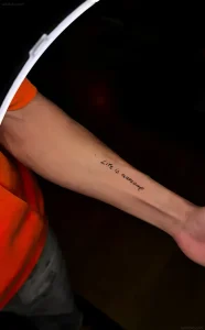 Татуировка на руке триатлета Тибо Эскэша с надписью 'Life is Awesome!'